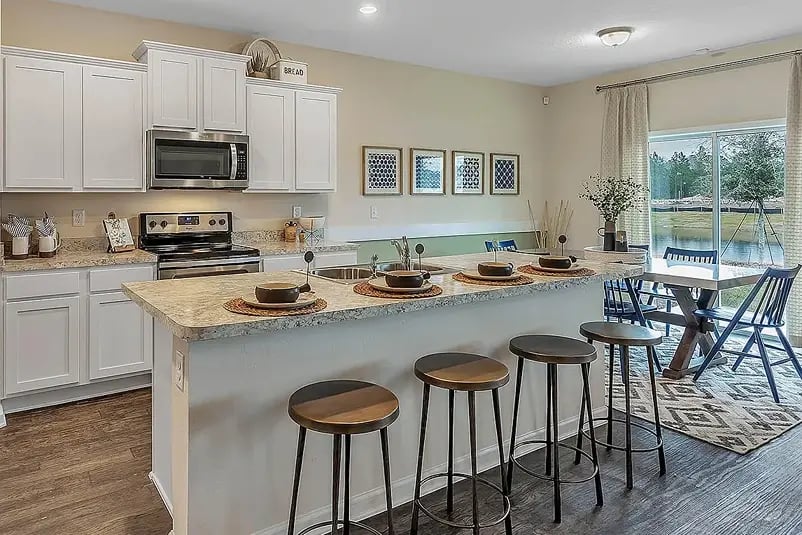 new homes in St. Augustine, FL. A kitchen with an island and dining room table and yellow walls. BRIGHTON-St Augustine, FL