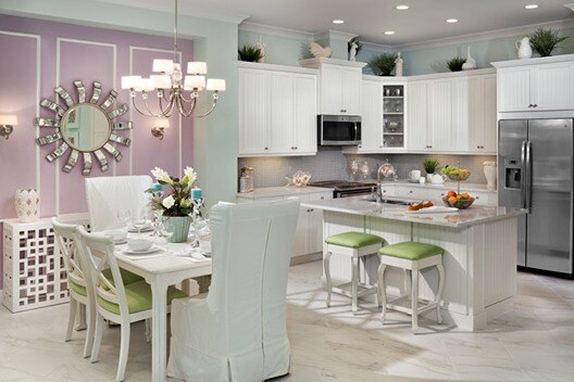 new homes in naples, fl. A modern kitchen with a pink wall, dining table with chairs and a kitchen island. 