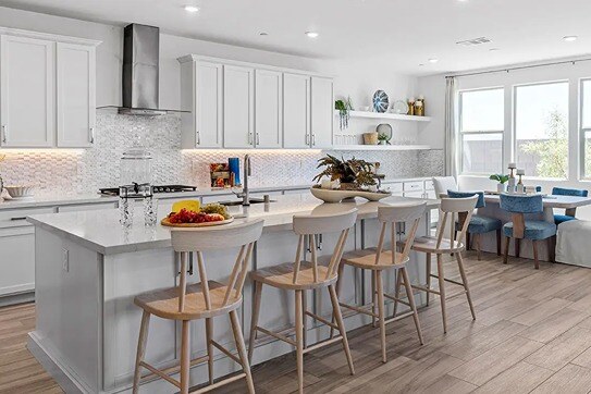 new homes in Las Vegas. A white kitchen with an island and four chairs. ISLA PLAN 3-Las Vegas, NV