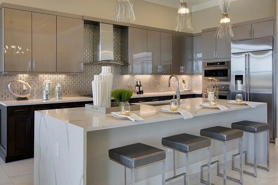 new home developments in sarasota, fl. A kitchen with grey cabinets and an island with white vases and place settings.