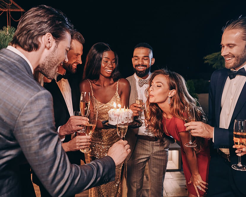 living in fort lauderdale. A woman blows out a birthday candle on a cake as her five friends watch, smiling.