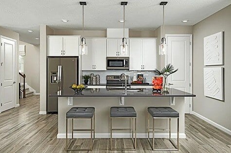 new homes in St. Augustine, FL. A kitchen with an island and three stools. PALM-St Augustine, FL