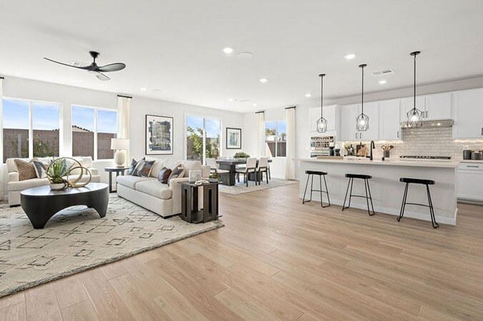 new homes in Las Vegas. A living room with couch and coffee table close to a kitchen with an island. ROSE 4-Las Vegas, NV