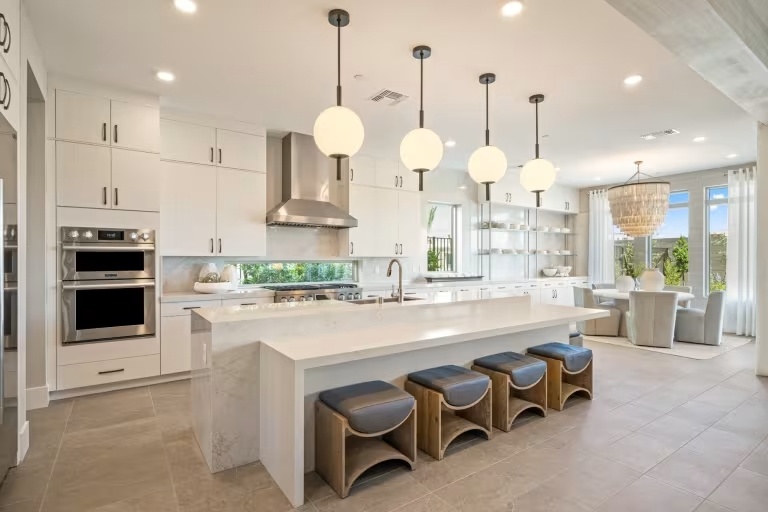 new homes in Las Vegas. A kitchen with light fixtures and dining room in the background. VITTORIA-Las-Vegas