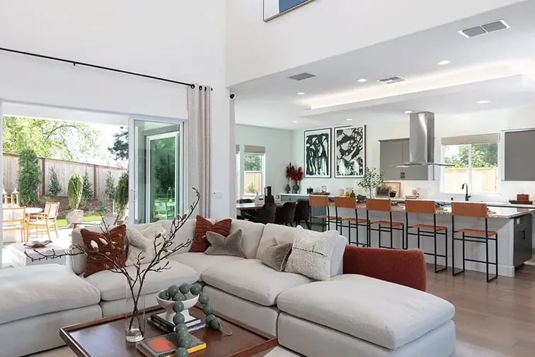 new homes in Antioch, CA. A living room with a white couch and kitchen in the background. WESTBURY-Antioch, CA