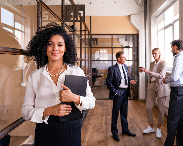 new home in austin. A businesswoman holding a laptop with three colleagues behind her.